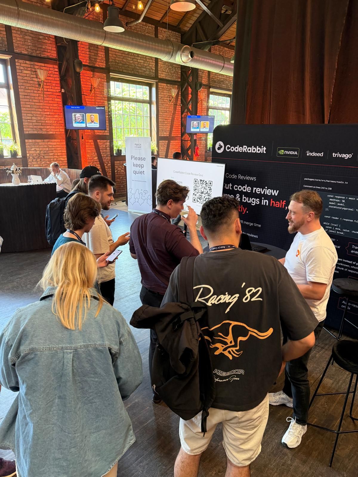 Group of people networking around a display at an indoor event or conference.